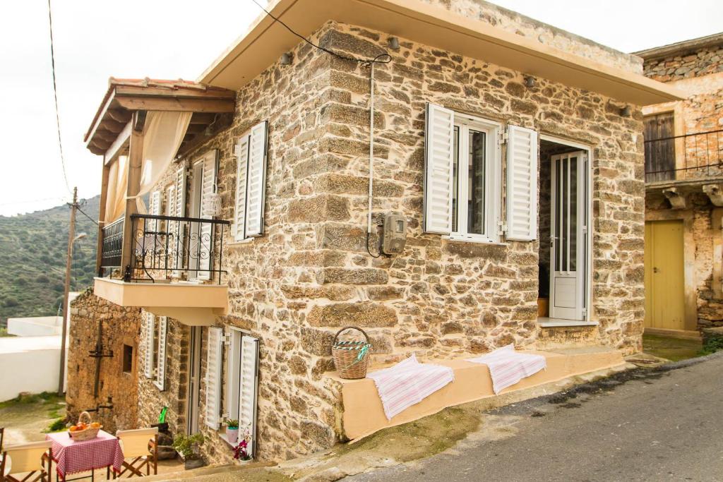a stone house with two benches on the side of it at Ktima Aikaterini in Séllai