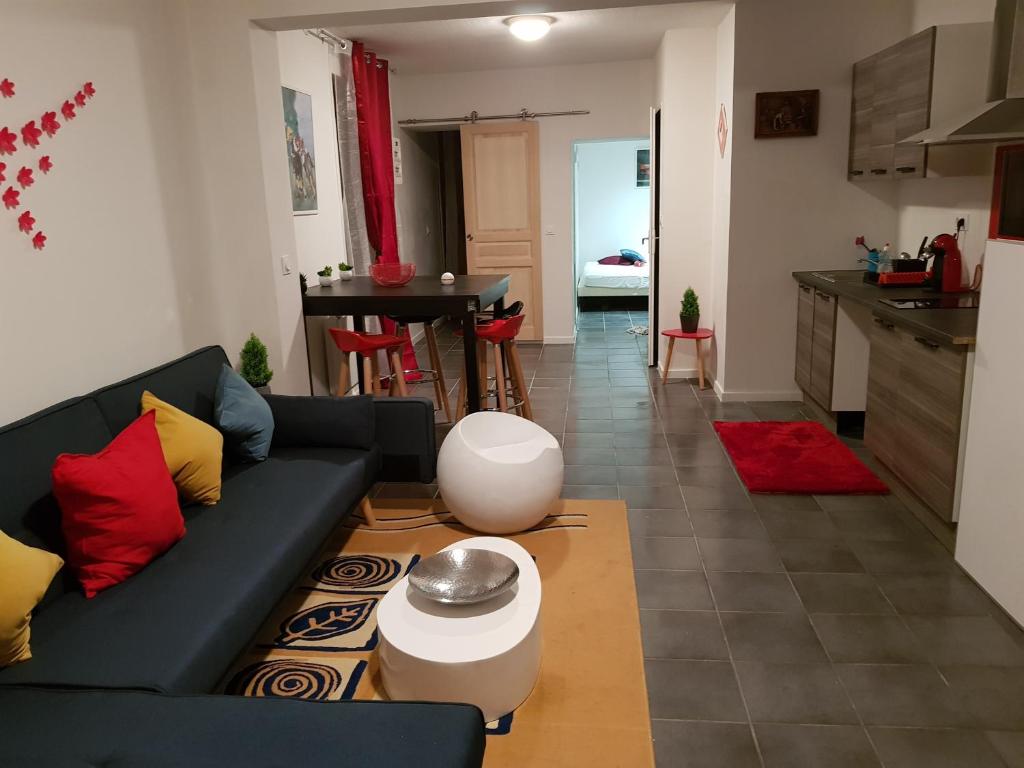 a living room with a black couch and a kitchen at Appartement moderne Roanne in Roanne