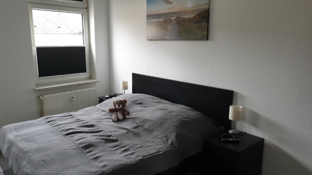 un osito de peluche sentado en una cama en un dormitorio en Goethe 3 - Mitten im Zentrum von Schwerin, en Schwerin