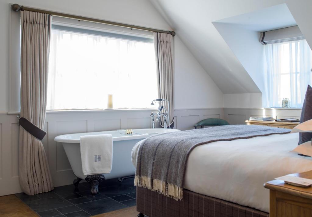 1 dormitorio con cama y bañera junto a una ventana en Hurley House Hotel en Hurley