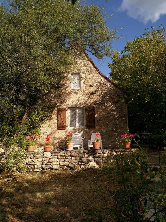 une maison en pierre avec deux chaises et une fenêtre dans l'établissement chez capy, à Frayssinet