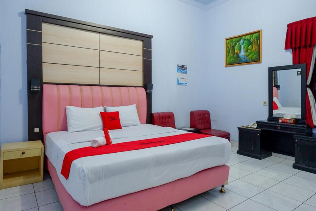 a bedroom with a bed with a pink headboard and a mirror at RedDoorz Plus Syariah near Stasiun Pekalongan 2 in Pekalongan
