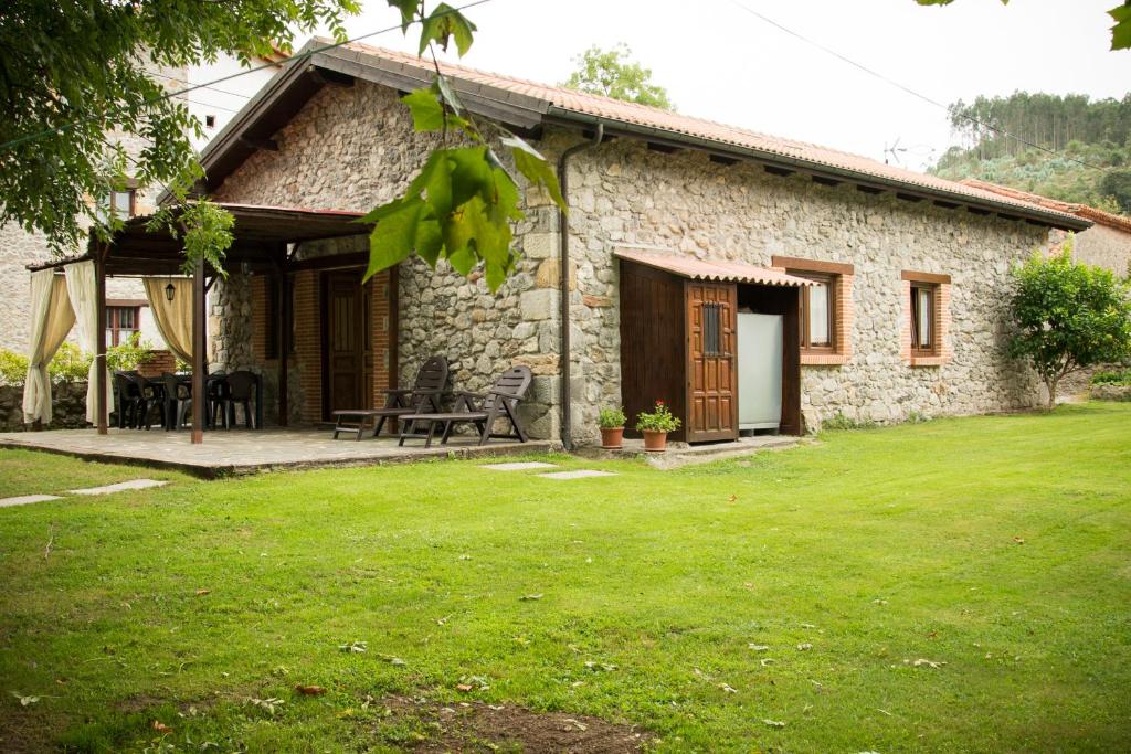 ein Steinhaus mit einer Terrasse und einem Rasenhof in der Unterkunft casa de maria in Hazas de Cesto