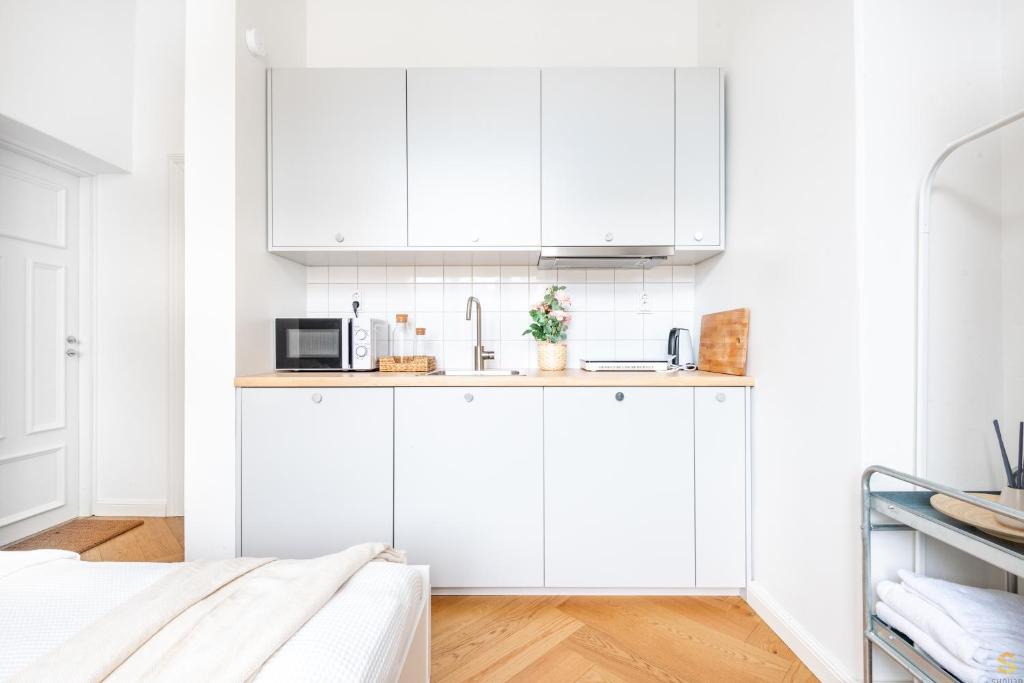 a white kitchen with white cabinets and a sink at Pieni Roobertinkatu Small 13 in Helsinki