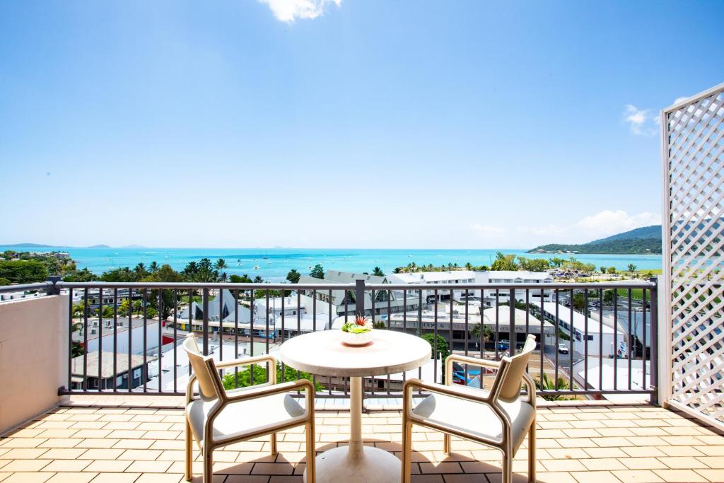 balcón con mesa, sillas y vistas al océano en OCEAN VIEWS 10, en Airlie Beach