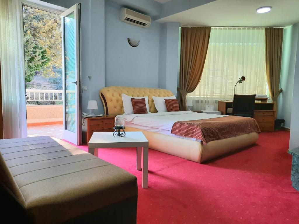 a bedroom with a bed and a desk and a window at Hotel Aristocrat & Fish Restaurant in Skopje