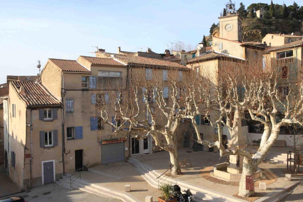 un gruppo di alberi in una città con una torre dell'orologio di Appartement de Charme - Parc du Luberon a Cadenet
