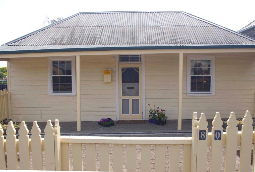 uma pequena casa com uma cerca branca em Darcy's Cottage on Piper em Kyneton