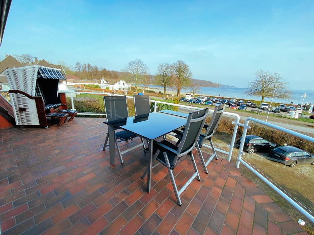 een patio met een tafel en stoelen op een balkon bij BEACH HOUSE-Traumwohnung in Bestlage mit herrlichem Meerblick in Harrislee