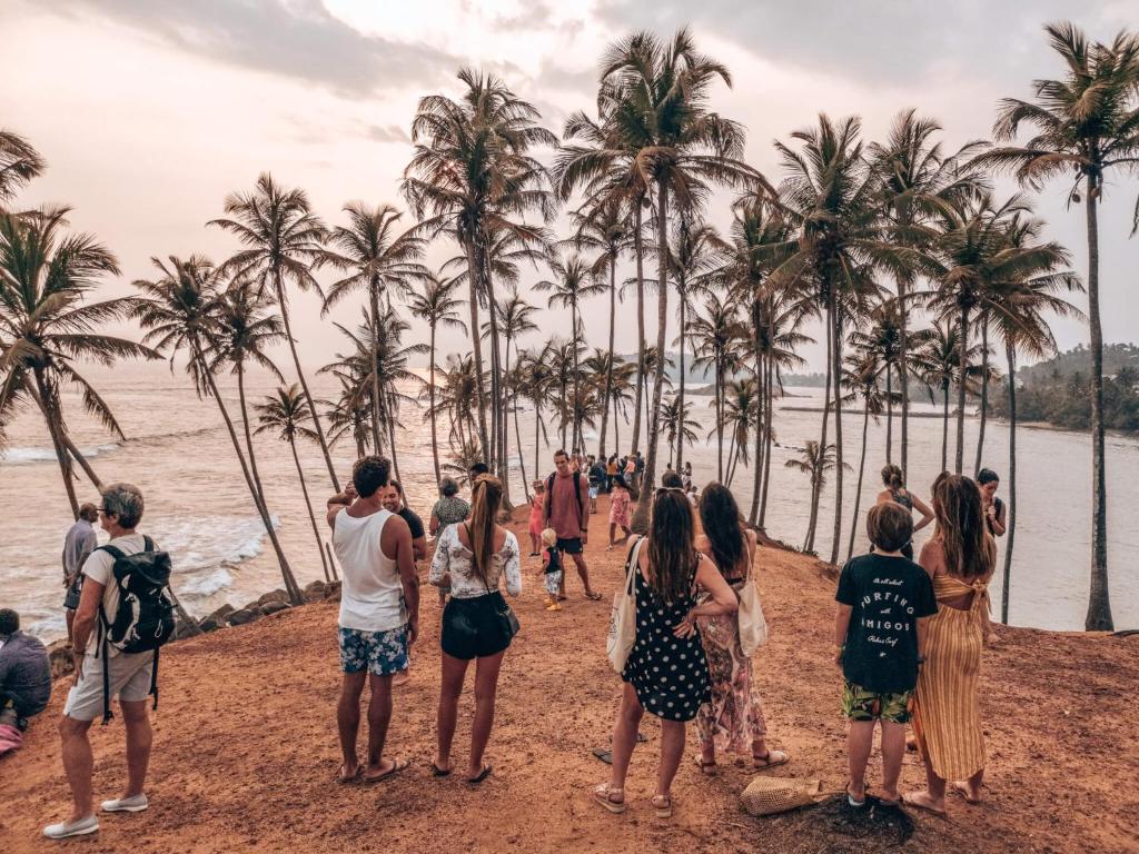 een groep mensen die op een strand met palmbomen staan bij Nature Inn in Mirissa