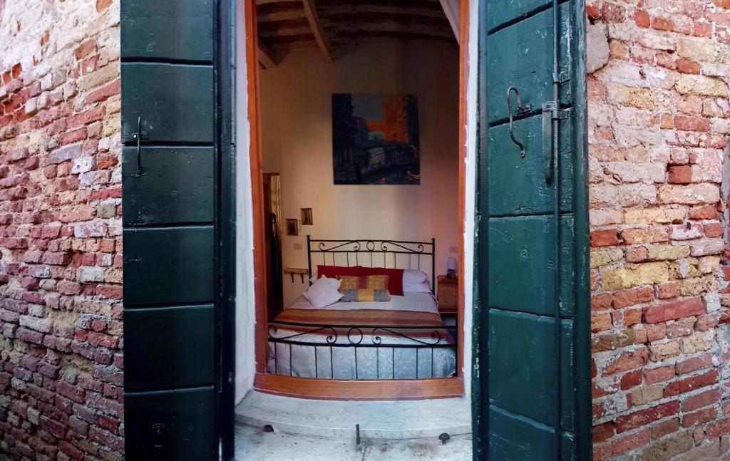 ヴェネツィアにある'BE HOME' SELF CHECK IN"SHORT-LONG TERMs" WELCOMEのレンガの壁の内側にベッドが備わるベッドルーム1室