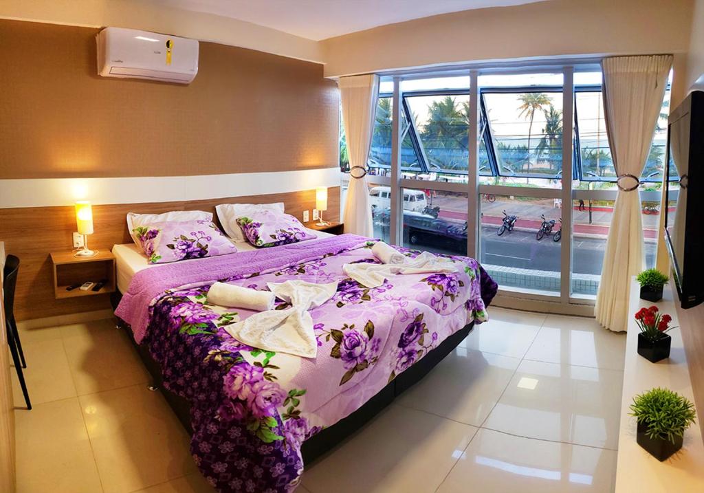 a bedroom with a purple bed and a large window at Flat Tambaú Solar do Atlântico in João Pessoa