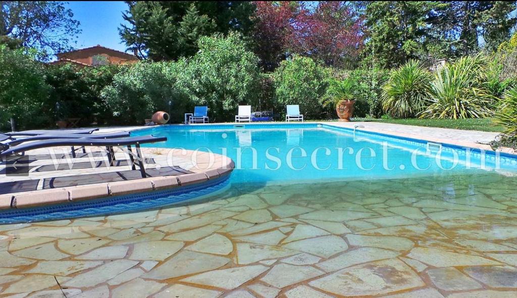 Una piscina en un patio con sillas alrededor. en Les Muscades, en Saint-Étienne-du-Grès