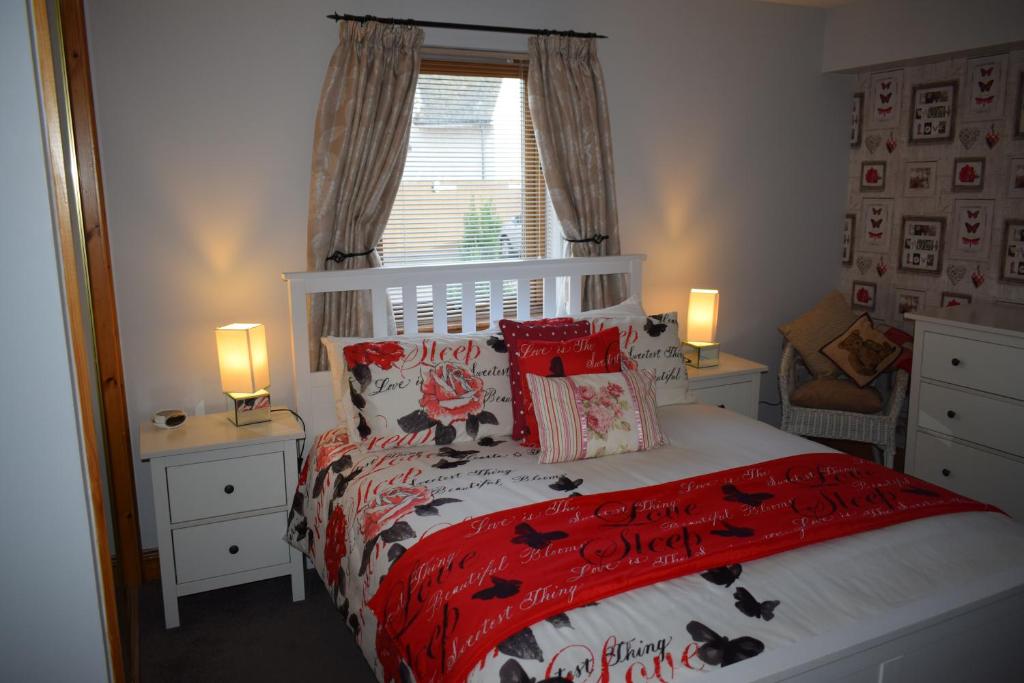 a bedroom with a bed with a red comforter and pillows at Dunroamin Self-Catering Apartment in Aviemore