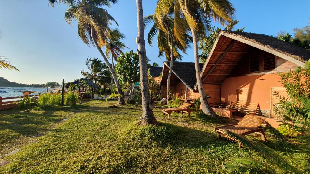 una casa con palmeras junto al agua en LE TRANSAT, en Ambatoloaka