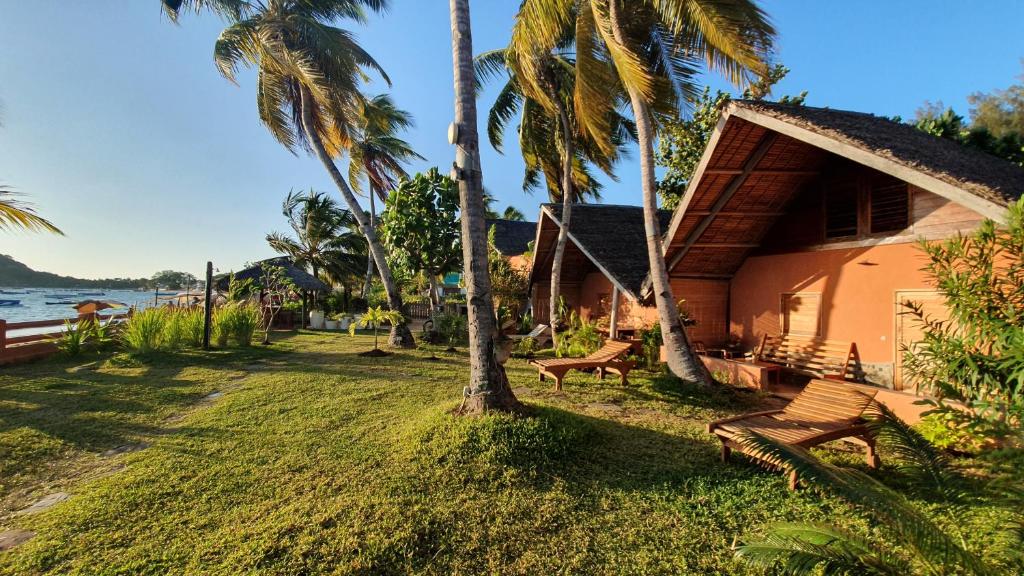a house with palm trees next to the water at LE TRANSAT in Ambatoloaka