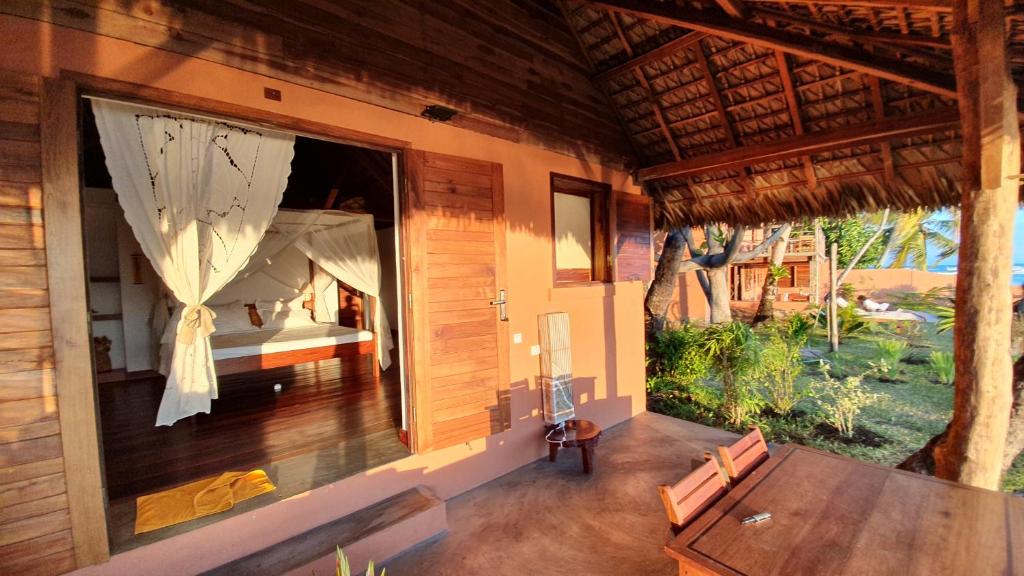 a room with a table and a bed in a house at LE TRANSAT in Ambatoloaka