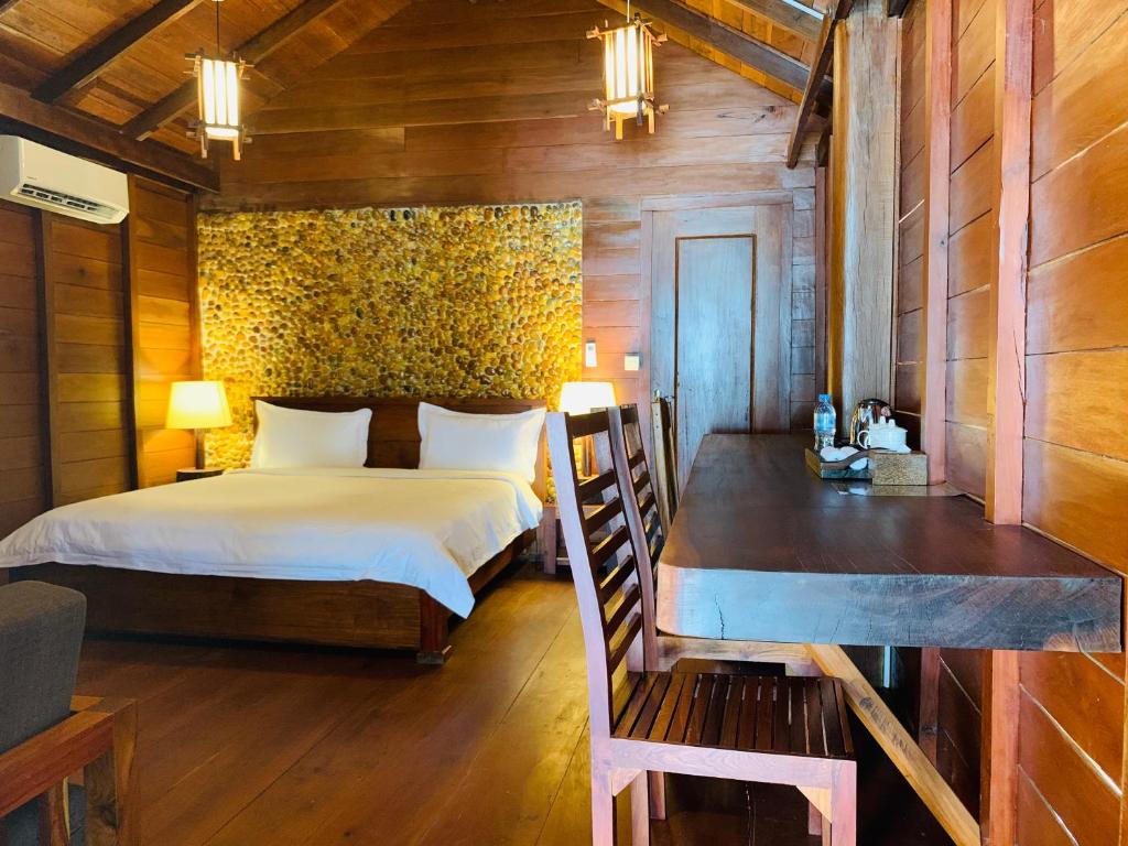 a bedroom with a bed and a desk in a room at Stung Treng Resort in Stœ̆ng Trêng