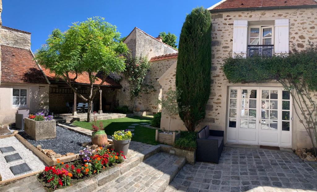 ein Haus mit einem Innenhof mit Blumen im Hof in der Unterkunft La Maison d'Emilie - Chambres d'hôtes in Chaumes-en-Brie