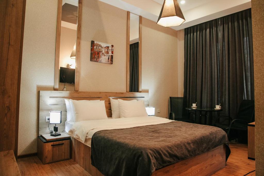 een hotelkamer met een bed en een spiegel bij City Heart Hotel in Tbilisi City