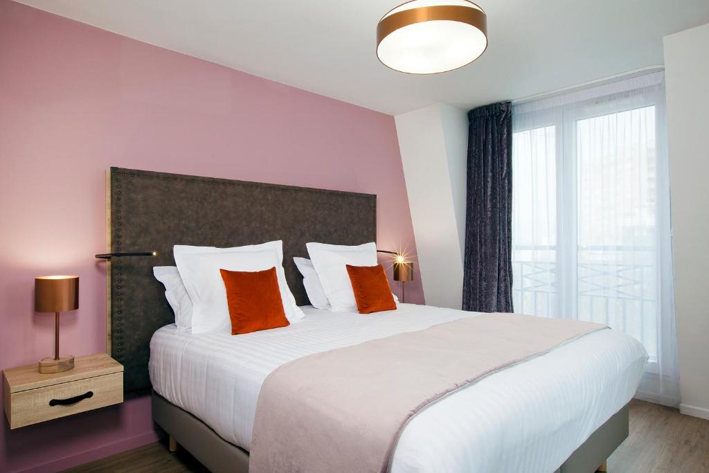 a bedroom with a large white bed with orange pillows at Residhome Puteaux La défense in Puteaux