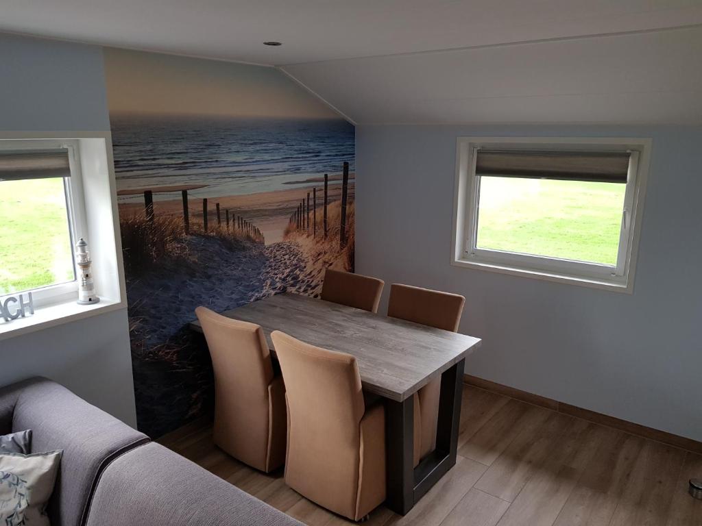 ein Esszimmer mit einem Tisch und Stühlen mit einem Gemälde des Ozeans in der Unterkunft Vakantiewoning Koegras in Julianadorp