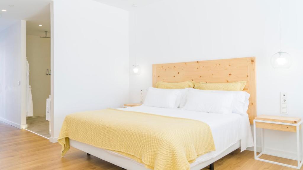 a bedroom with a large white bed with a yellow blanket at CalaLanzarote Suites Hotel - Adults Only in Playa Blanca