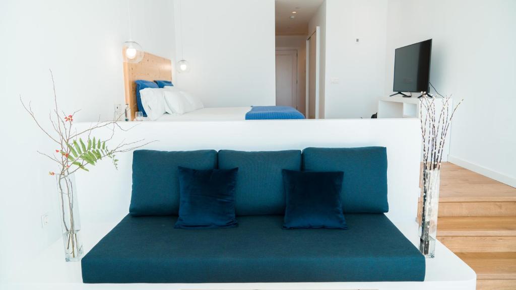a blue couch in a room with a bed at CalaLanzarote Suites Hotel - Adults Only in Playa Blanca