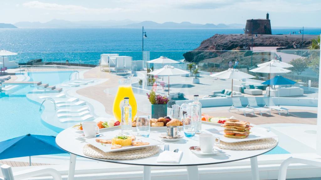 a table with food on it next to a pool at CalaLanzarote Suites Hotel - Adults Only in Playa Blanca