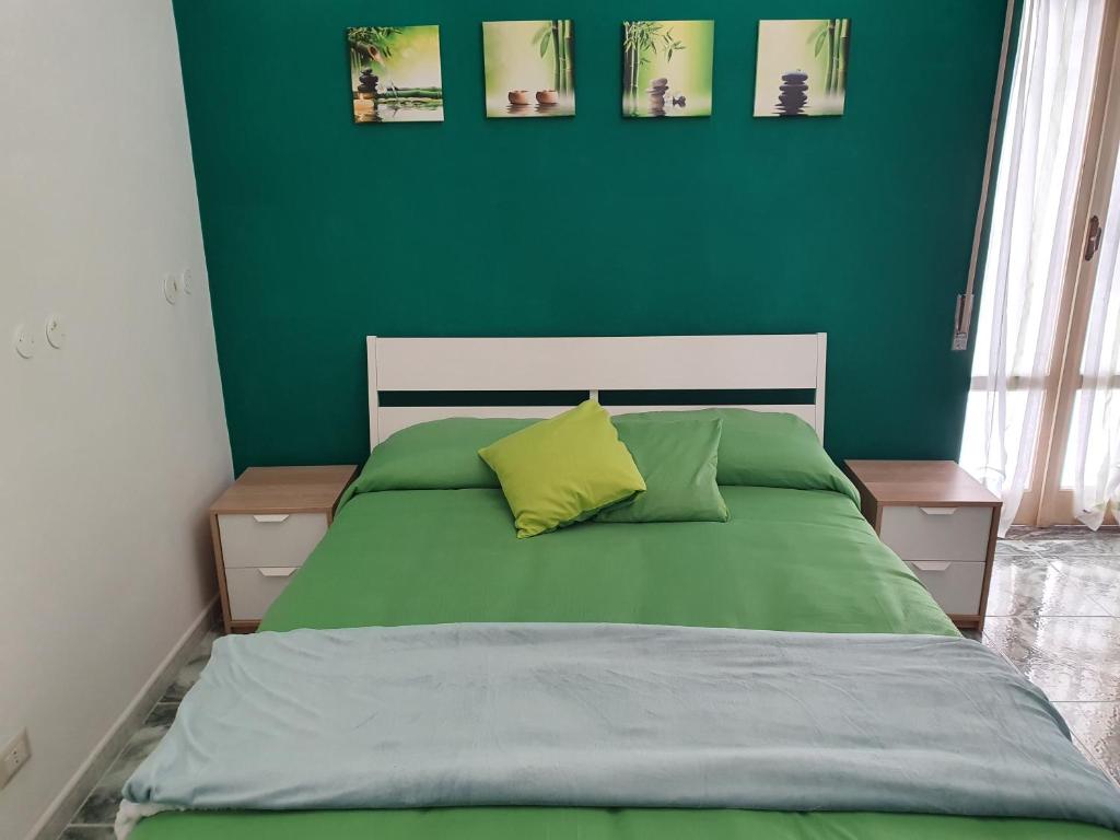 een groene slaapkamer met een bed met 2 kussens bij Capri View in Torre del Greco