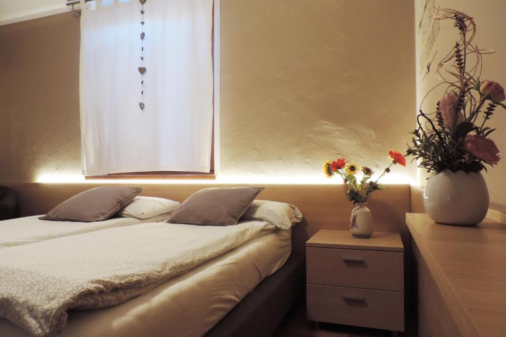 a bedroom with a bed and a window with flowers at B&B Casa Vanzetta in Ziano di Fiemme