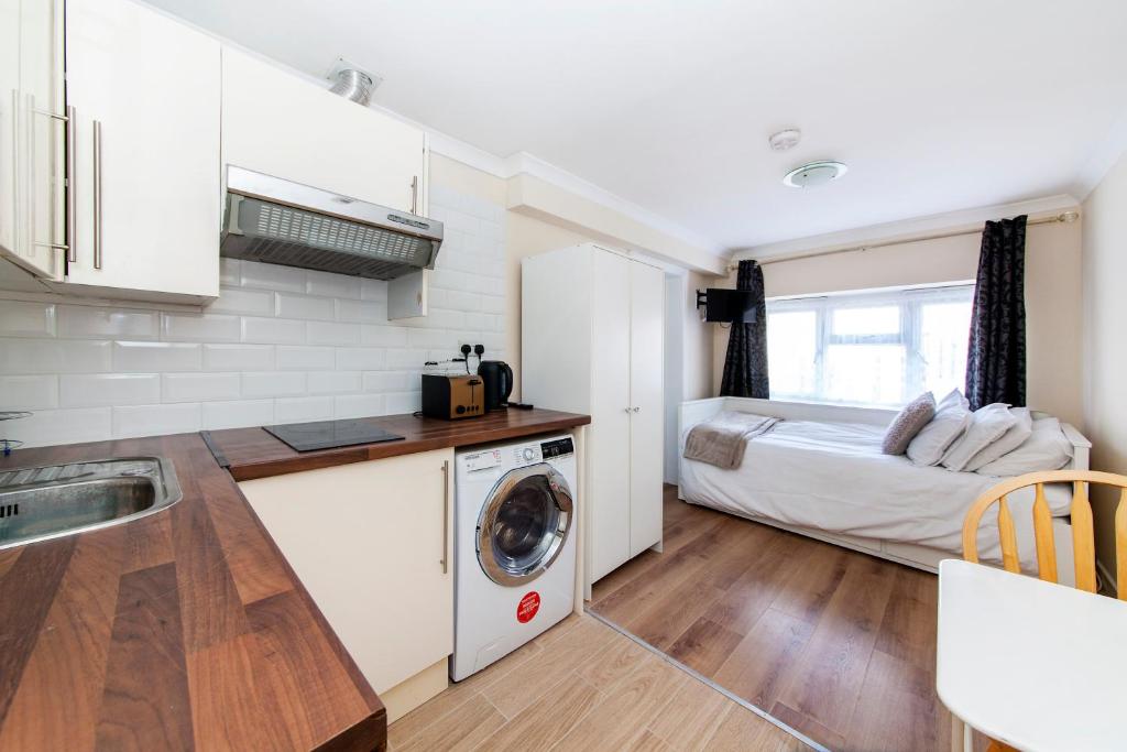 uma cozinha com máquina de lavar e secar roupa ao lado de uma cama em TH Serviced Apartment London em Northolt