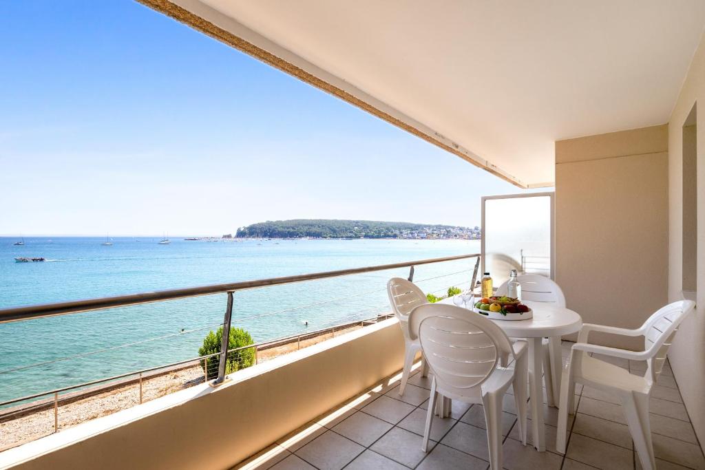 Résidence Pierre & Vacances Cap-Morgat في كروزون: شرفة مع طاولة وكراسي وإطلالة على المحيط