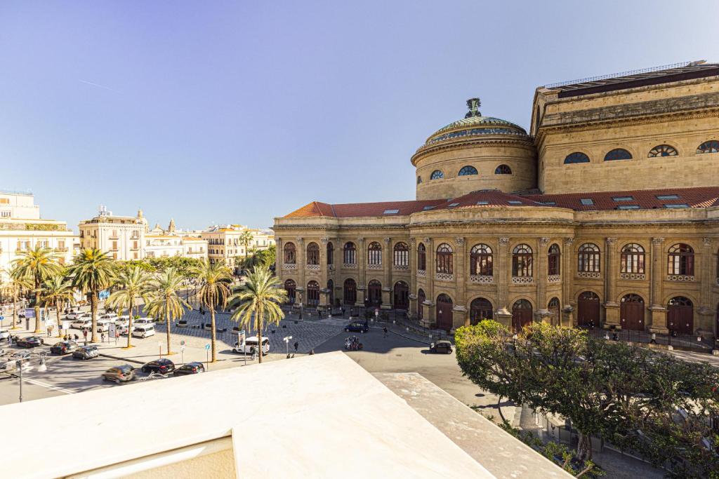 a large building with palm trees in front of it at Solemar Sicilia - Palazzo Massimo in Palermo