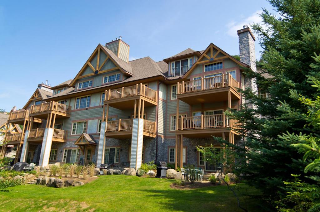 a large house with a large yard in front of it at Les Falaises by Tremblant Platinum in Mont-Tremblant