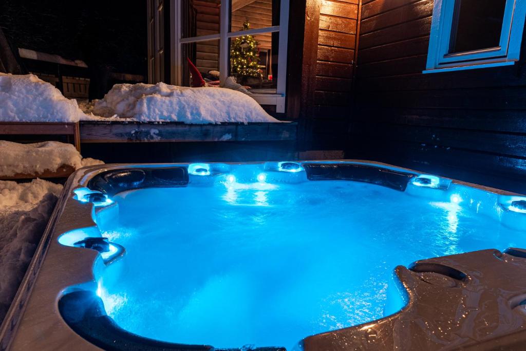 uma banheira de hidromassagem com luzes azuis na neve em Cabin in Hodlekve with 5 bedrooms & hot tub. em Sogndal
