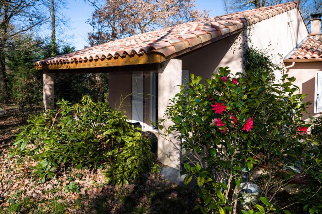 ein Haus mit einem gefliesten Dach und ein paar Blumen in der Unterkunft Gîte Les chênes in Fontenilles