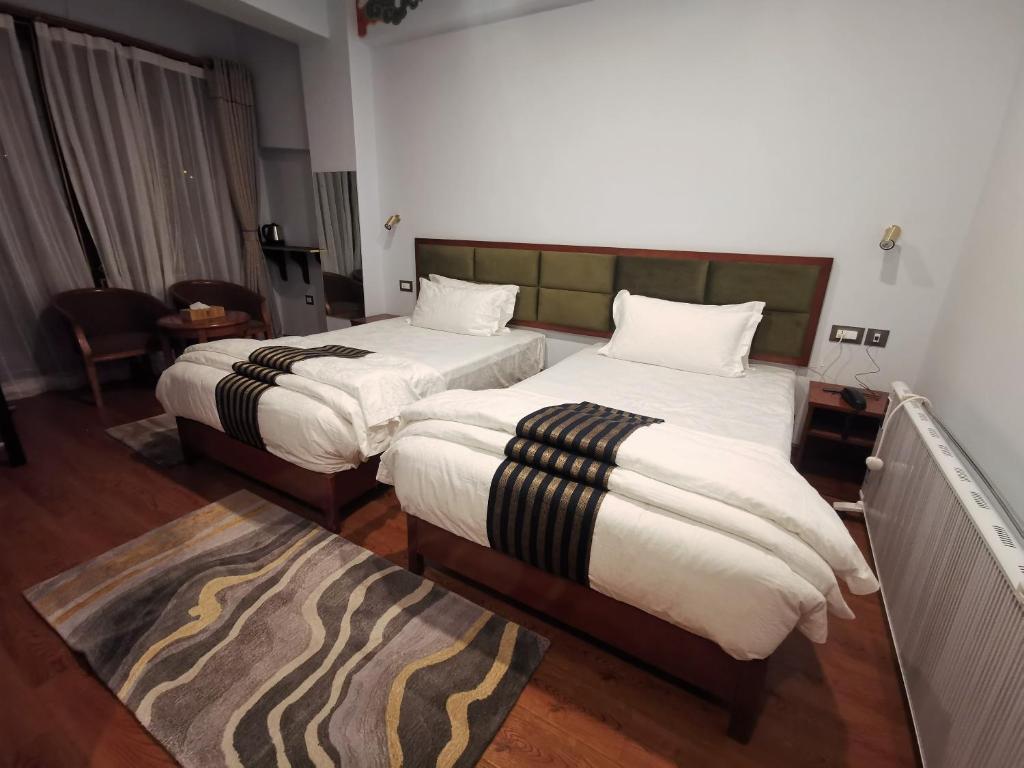 a hotel room with two beds and a rug at Ludrong Hotel in Thimphu
