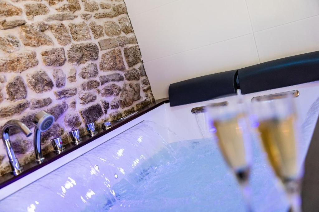 two glasses of champagne sitting next to a swimming pool at La Suite de l'Etoile in Longmesnil