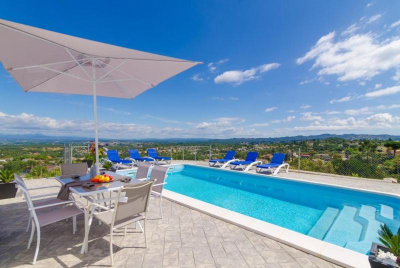 einen Pool mit einem Tisch, Stühlen und einem Sonnenschirm in der Unterkunft Club Villamar - Maxmara in Vidreres