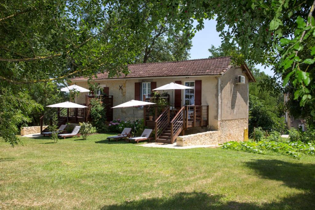 a house with chairs and umbrellas in a yard at Les Hauts de Condom Appartements Climatises in Condom
