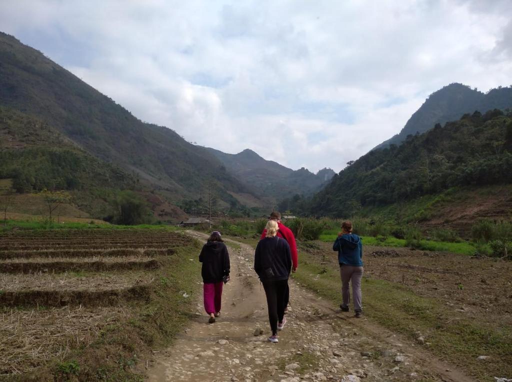 a group of people walking down a dirt road at Be's Home & Tours in Ha Giang