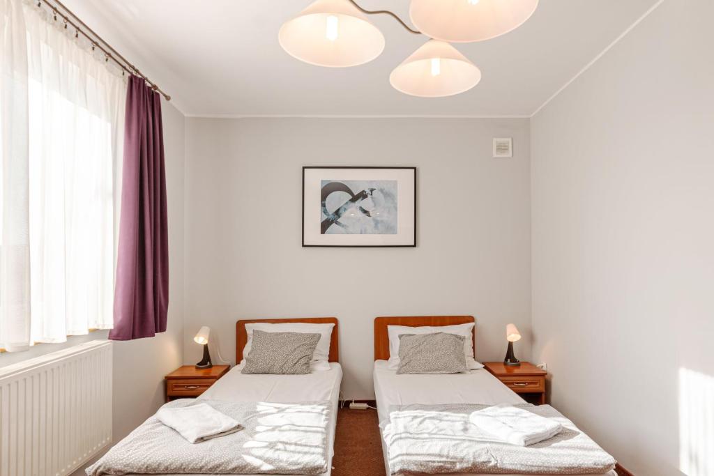 ドンブロヴァ・グルニチャにあるZajazd Bachusの白い壁の客室内のベッド2台