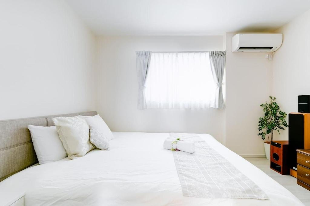 - un lit blanc dans une chambre avec fenêtre dans l'établissement Osaka - House / Vacation STAY 74031, à Osaka