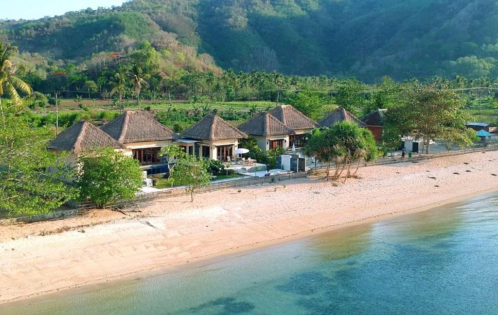 a row of houses on a beach next to the water at Star Sand Beach Resort in Sekotong