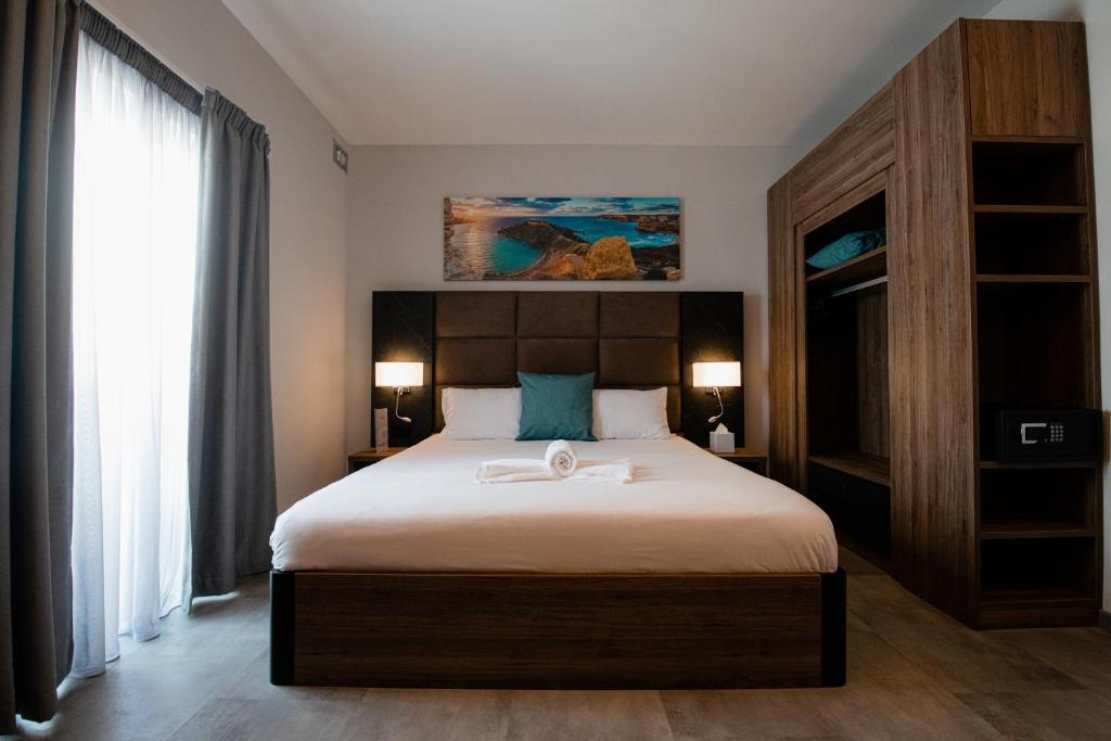 a bedroom with a large bed with a wooden headboard at Pebbles Resort in St. Paul's Bay