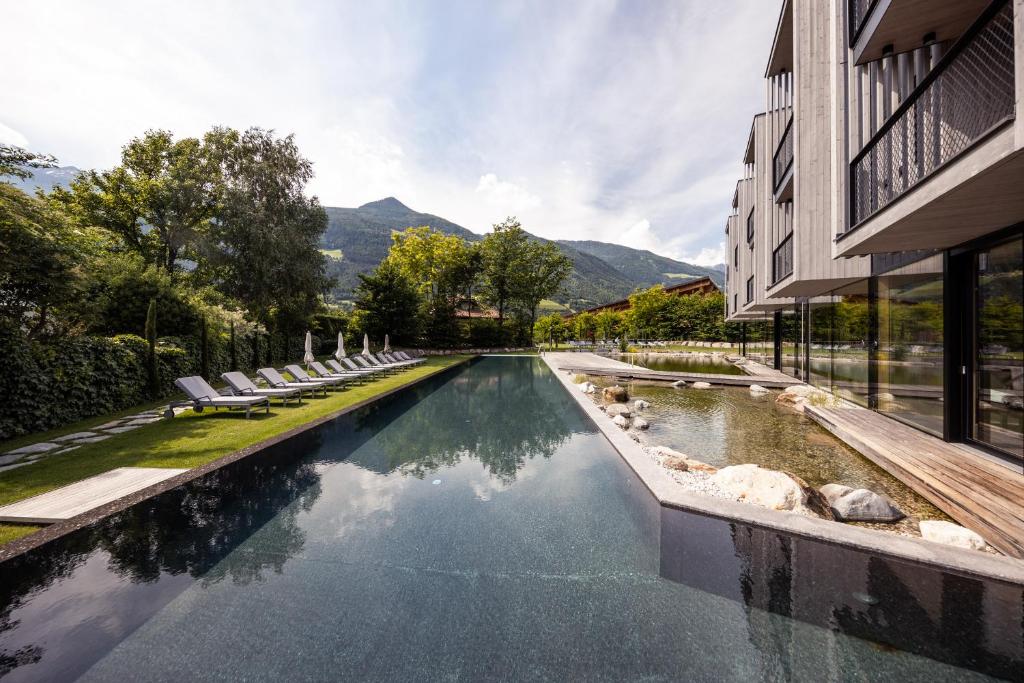 een zwembad met stoelen naast een gebouw bij Hotel Sand in Castelbello