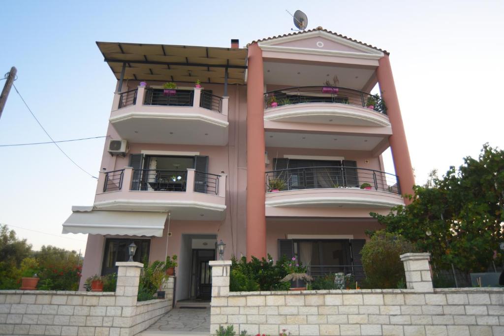 un grande edificio rosa con balconi di Georgias House a Città di Lefkada