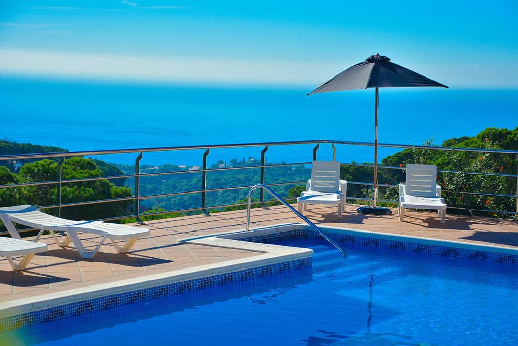 una piscina con 2 sillas y una sombrilla en Club Villamar - Serra Brava, en Lloret de Mar