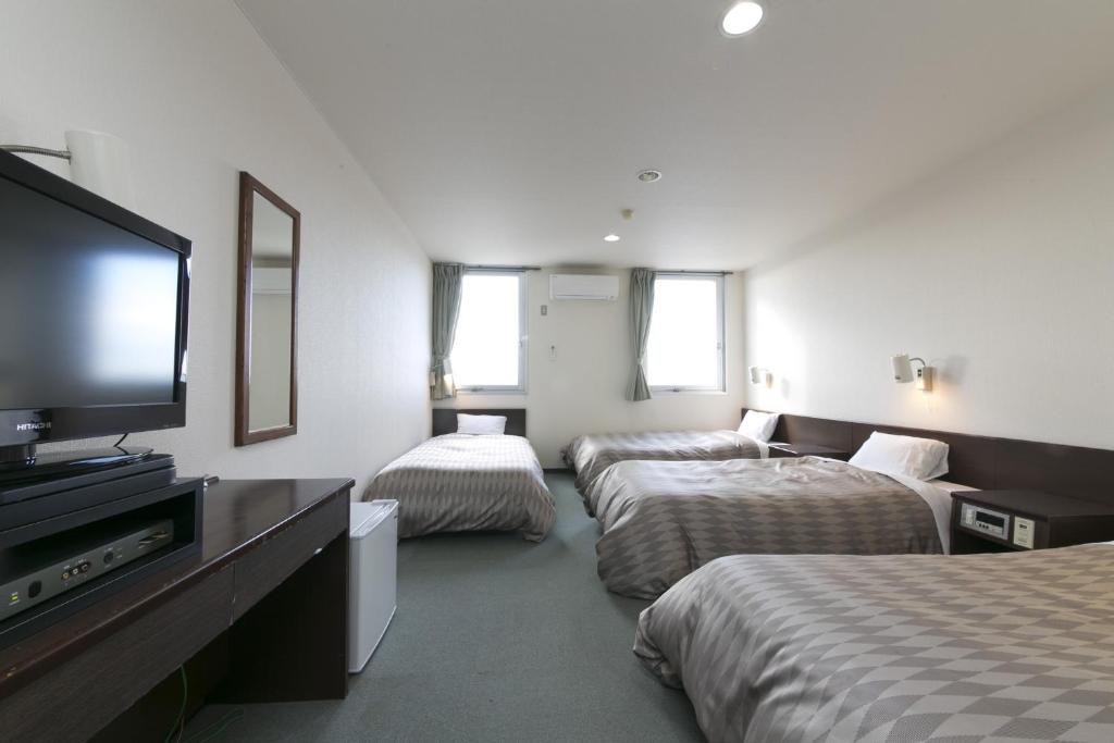 een hotelkamer met drie bedden en een flatscreen-tv bij Okadaya Bayside / Vacation STAY 72738 in Toyohashi